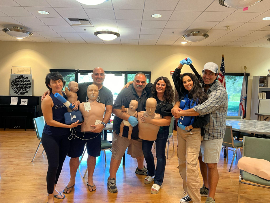 CPR class holding adult and infant training manikins after certification
